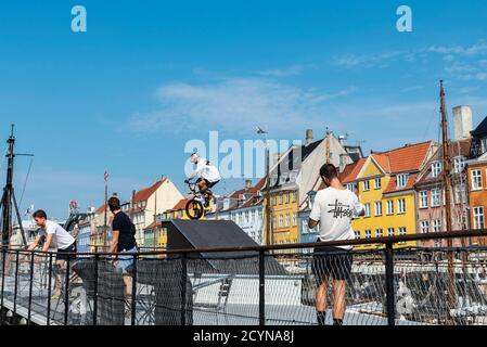 Copenhagen, Danimarca - 27 agosto 2019: Un giovane che fa acrobazie in bicicletta su una barca con gente intorno a Nyhavn, Copenhagen, Danimarca Foto Stock