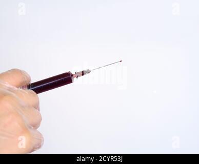 Una mano in un guanto di lattice contiene una siringa. Il medico contiene una siringa per la vaccinazione. Foto Stock