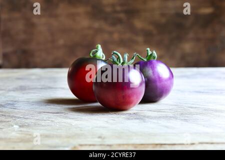 Pomodori blu insoliti in diverse fasi di maturazione su a. sfondo di legno Foto Stock