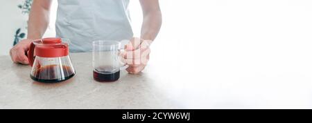 Caffè appena fatto in paniera di vetro e tazza di vetro sul tavolo. Pourover, V60. Foto Stock