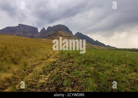 Il picco del cowl del monaco, con le nuvole di tempesta sullo sfondo delle montagne Drakensberg in Sudafrica Foto Stock