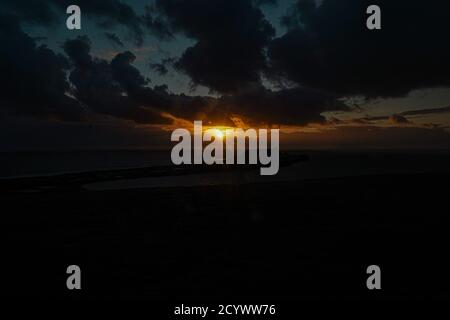 Tramonto su Gower Peninsular Rhossilli Bay Worm Rock formazione rossa cieli Foto Stock