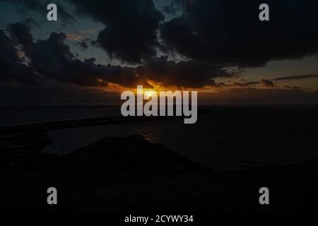 Tramonto su Gower Peninsular Rhossilli Bay Worm Rock formazione rossa cieli Foto Stock