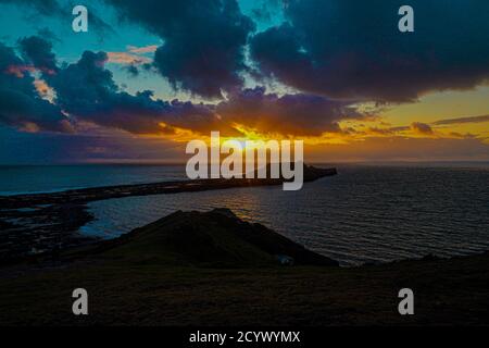 Tramonto su Gower Peninsular Rhossilli Bay Worm Rock formazione rossa cieli Foto Stock