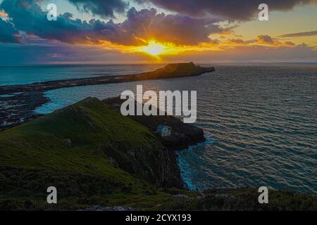 Tramonto su Gower Peninsular Rhossilli Bay Worm Rock formazione rossa cieli Foto Stock