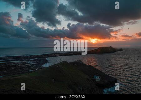 Tramonto su Gower Peninsular Rhossilli Bay Worm Rock formazione rossa cieli Foto Stock