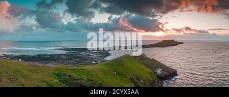 Tramonto su Gower Peninsular Rhossilli Bay Worm Rock formazione rossa cieli Foto Stock