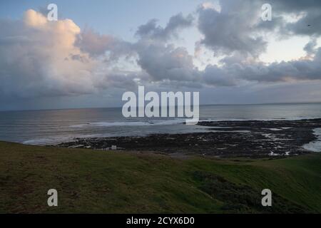 Tramonto su Gower Peninsular Rhossilli Bay Worm Rock formazione rossa cieli Foto Stock