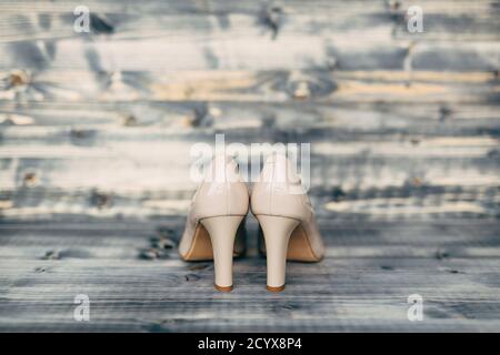 Scarpe da sposa beige con tacco alto e texture in legno grigio. Foto Stock