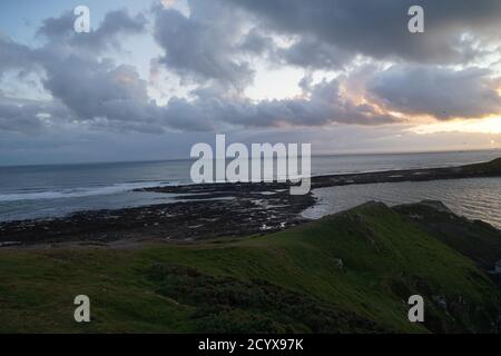 Tramonto su Gower Peninsular Rhossilli Bay Worm Rock formazione rossa cieli Foto Stock