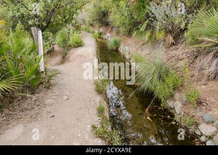 Antica acequia o séquia corso d'acqua gestito dalla comunità utilizzato per l'irrigazione su un sentiero. Benahavis, Andalusia, Spagna. Foto Stock
