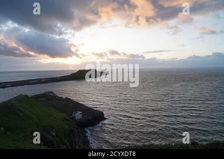 Tramonto su Gower Peninsular Rhossilli Bay Worm Rock formazione rossa cieli Foto Stock