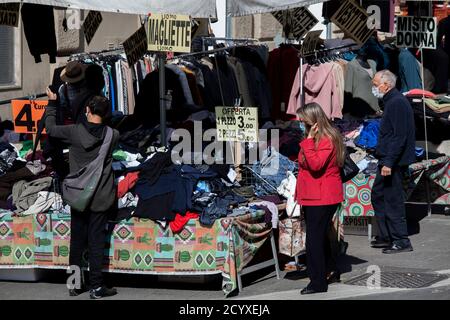 ROMA, ITALIA - OTTOBRE 01 2020: I pedoni si accavallano per i vestiti in vendita in uno stand di mercato a Roma, Italia. Foto Stock