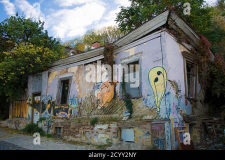 Una vecchia casa in mattoni abbandonata in rovina con graffiti, cresciuta con erba verde e alberi. Kiev, Ucraina Foto Stock