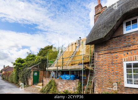 Un thatcher esperto al lavoro che sostituisce il tetto tradizionale di paglia di un vecchio cottage in Great Bedwyn, un villaggio nel Wiltshire orientale, Inghilterra meridionale Foto Stock