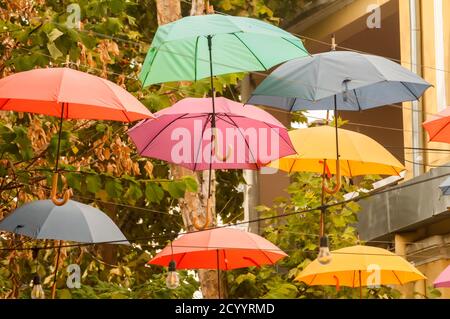 Ombrelloni in diversi colori appesi sulla strada della città Foto Stock