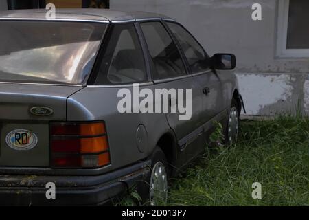 Auto d'epoca degli anni '80 abbandonata in un cortile. Vista laterale dell'auto vintage grigio, Foto Stock
