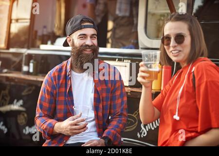 Una coppia di hipster che si rilassa con la birra davanti al cibo carrello Foto Stock
