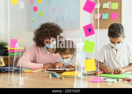 Insegnante con bambini che indossano maschera in classe prescolare durante pandemia del virus corona Foto Stock