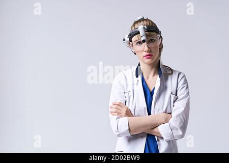 Medico di fiducia che indossa la lampada frontale chirurgica e gli occhiali protettivi. Ritratto di otolaringologo femminile o chirurgo capo e collo Foto Stock