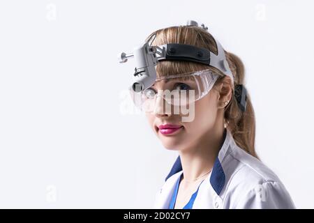 Medico di fiducia che indossa la lampada frontale chirurgica e gli occhiali protettivi. Closeup ritratto di otolaringologo femminile o testa e collo Foto Stock