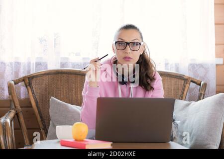 Giovane donna intelligente in studi di abbigliamento casual a casa, scrive to-do elenco, fa piani Foto Stock