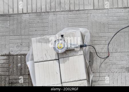 Smerigliatrice angolare su una pila di piastrelle per pavimentazione. Predellino in riparazione. Sfondo della costruzione. Spazio di copia Foto Stock