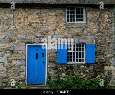 West Lulworth, Regno Unito - 19 luglio 2020: Bella casa di cottage con tetto di paglia con porte e persiane color blu cobalto, Dorset unico colorfull Foto Stock