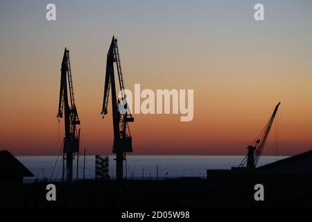 Genova, Italia. Silhouette cantieri navali gru a Genova Sestri Ponente al tramonto contro i suggestivi colori del cielo e del mare Foto Stock