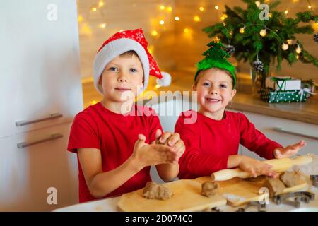 I bambini felici stanno preparando il pan di zenzero alla vigilia del nuovo anno. Ragazzo e ragazza in cucina in attesa di Natale. I bambini fanno i biscotti di festa a casa. Foto Stock