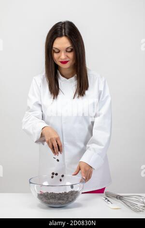 Bel pasticcere che fa il cioccolato artigianale, versa gocce di cioccolato fondente Foto Stock