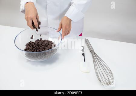 Il cioccolatiere Closeup versa gocce di cioccolato fondente isolate su sfondo bianco Foto Stock