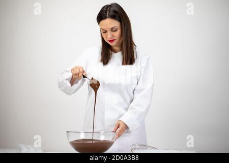 L'attraente cioccolatiere brunette in uniforme bianca produce cioccolato di lusso Foto Stock