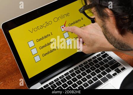 Persona che vota sul computer tramite Internet con Testo votazione online in portoghese Foto Stock