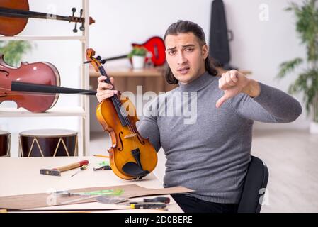 Giovane uomo riparatore che ripara il violino in officina Foto Stock