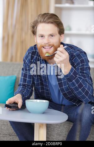 uomo con una ciotola di cereali guardando la tv Foto Stock