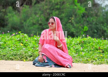 Una giovane donna in posa in giardino con occhiali da sole Foto Stock