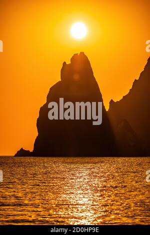 Un tramonto in oro con la sagoma di un promontorio roccioso sul mare. Spazio di copia. Il concetto di calma, silenzio e unità con la natura. capo Foto Stock