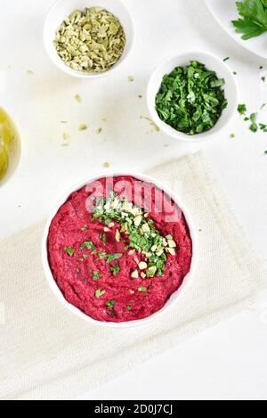 Hummus di barbabietola fatto in casa in ciotola su sfondo di pietra bianca. Vista dall'alto, disposizione piatta Foto Stock