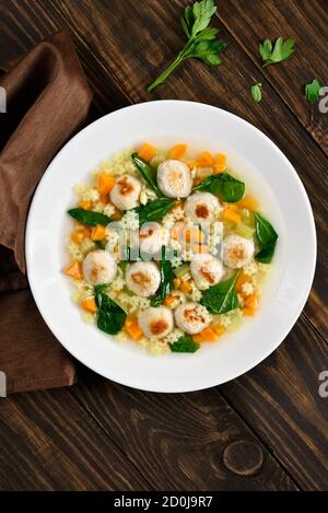 Zuppa italiana di nozze con polpette, verdure e piccola pasta in ciotola su fondo di legno. Piatto di dieta sana per cena. Vista dall'alto, disposizione piatta Foto Stock