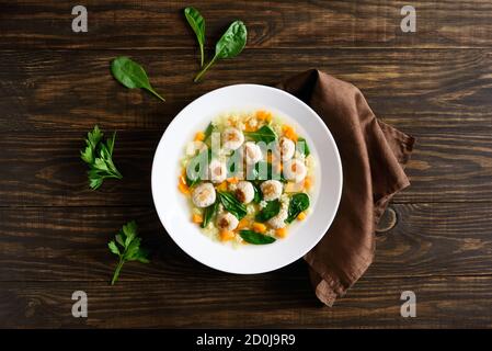 Zuppa italiana di nozze con polpette, verdure e piccola pasta in ciotola su fondo di legno. Piatto di dieta sana per cena. Vista dall'alto, disposizione piatta Foto Stock