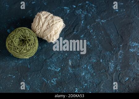 Palle colorate matassa di filo di lana per uncinetto e maglia su cemento mastice di tessitura blu scuro. Immagine flatlay con spazio per il testo. Foto Stock