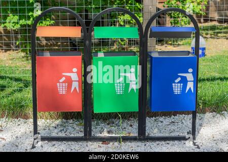 Bidoni colorati per smistare i rifiuti nel parco. Concetto di raccolta e riciclaggio dei rifiuti separati Foto Stock