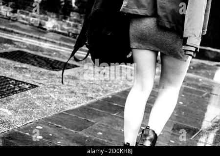 Young Woman Walking Home in the Rain indossa una piccola gonna aderente, Crop Chiudi in bianco e nero Foto Stock