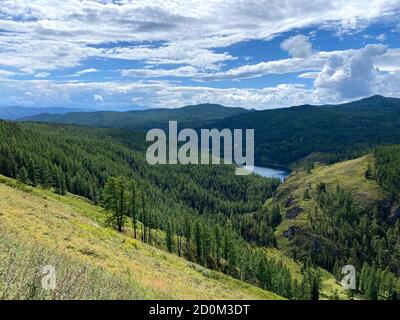 Paesaggio montano all'aperto che raffigura nuvole, conifere e prati Foto Stock