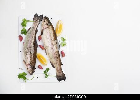 Due trote grezze con spezie e limone su sfondo bianco, vista dall'alto Foto Stock