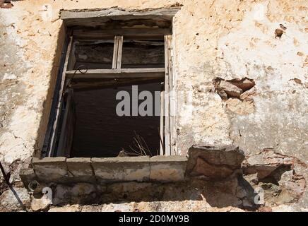 Una vecchia finestra che appartiene ad una casa abbandonata situata in un villaggio alto nella zona montagnosa di Psiloritis, Creta, Grecia. Foto Stock