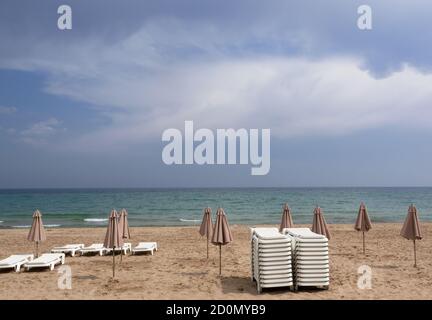 ombrelloni chiusi negli stabilimenti balneari sulla spiaggia una giornata nuvolosa alla fine della stagione Foto Stock