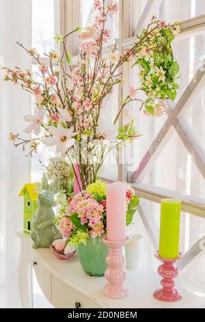 Decorazione degli interni di Pasqua. Composizione Beatuful con candele, uova, coniglio, casa di uccelli e rami di mela fiorente. Foto Stock