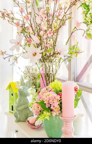 Decorazione degli interni di Pasqua. Composizione Beatuful con candele, uova, coniglio, casa di uccelli e rami di mela fiorente. Foto Stock